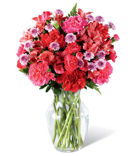 Flower arrangement in a clear glass vase featuring pink, red, and lavender blooms, shown as a classic Valentine&rsquo;s bouquet.